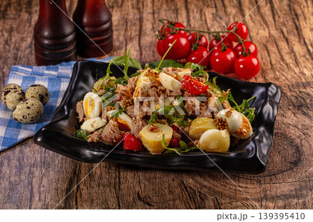 Fresh tuna salad with boiled eggs, potatoes, tomatoes, and arugula on a rustic wooden table Fresh tuna salad with boiled eggs, potatoes, tomatoes, and arugula on a rustic wooden table 139395410