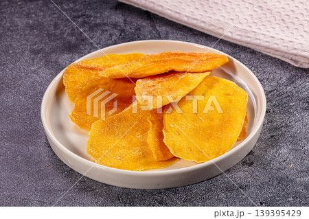 Dried mango slices on white plate. Healthy snack, sweet fruit dessert, tropical food Dried mango slices on white plate. Healthy snack, sweet fruit dessert, tropical food 139395429