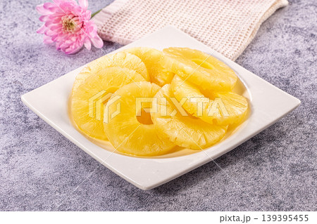 Bright Yellow Canned Pineapple Rings on White Plate with Pink Flower and Textured Cloth 139395455