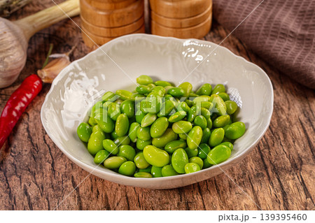Fresh Green Edamame Beans in White Bowl on Rustic Wooden Table with Garlic and Chili Fresh Green Edamame Beans in White Bowl on Rustic Wooden Table with Garlic and Chili 139395460