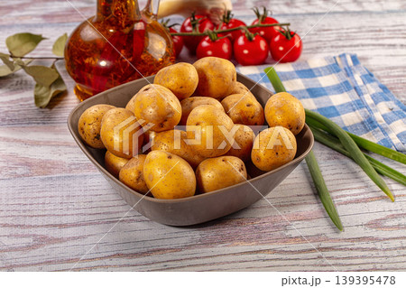 Bowl of fresh new potatoes with cherry tomatoes and green onions on wooden table 139395478