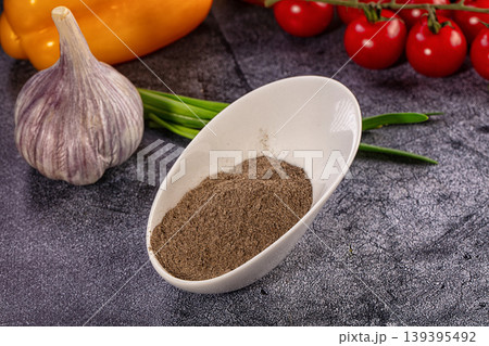 Ground black pepper in white bowl with fresh vegetables. Culinary ingredients like garlic, tomato, and onion on dark background Ground black pepper in white bowl with fresh vegetables. Culinary ingredients like garlic, tomato, and onion on dark background 139395492