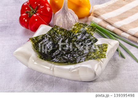 Crispy nori seaweed snack in white bowl with fresh bell peppers and garlic 139395498