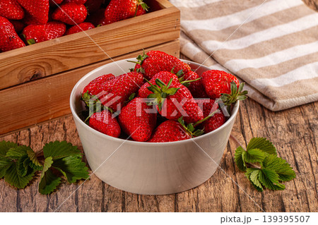 Fresh ripe strawberries in white bowl and wooden crate on rustic table Fresh ripe strawberries in white bowl and wooden crate on rustic table 139395507
