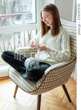 Woman knitting new sweater with gray yarn at home Woman knitting new sweater with gray yarn at home 139395576