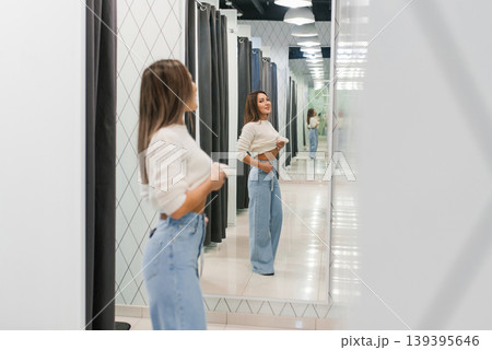 Young Woman Trying Jeans In Fitting Room Young Woman Trying Jeans In Fitting Room 139395646