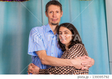 Caucasian couple embracing in a friendly pose, wearing casual clothing, with a light blue background decorated with festive elements Caucasian couple embracing in a friendly pose, wearing casual clothing, with a light blue background decorated with festive elements 139395792
