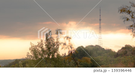 Dramatic sunset sky over a distant TV tower and lush green forest canopy Dramatic sunset sky over a distant TV tower and lush green forest canopy 139396446