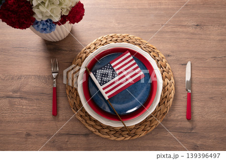 Patriotic table setting with American flag and plates on wooden table Patriotic table setting with American flag and plates on wooden table 139396497