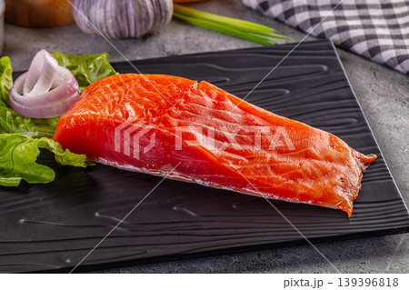 Raw salmon fillet on black plate with fresh ingredients for cooking. 139396818