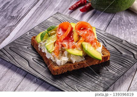 Avocado toast with cream cheese on a rustic wooden board with fresh ingredients 139396819