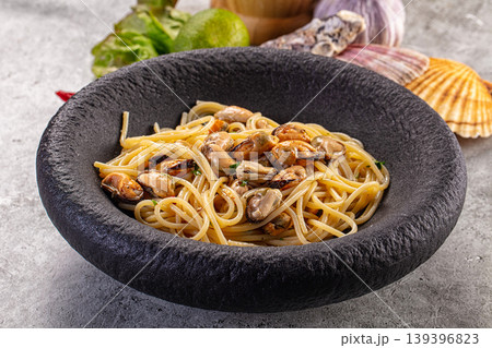 Spaghetti with mussels and herbs in a rustic black bowl. 139396823