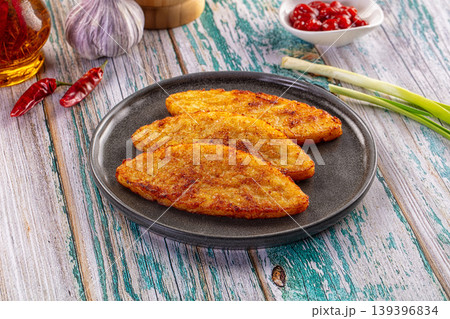 Golden fried potato pancakes on a gray plate with fresh ingredients on a rustic wooden background. Golden fried potato pancakes on a gray plate with fresh ingredients on a rustic wooden background. 139396834