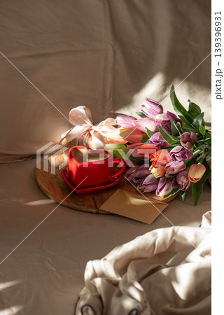 Heart Shaped Coffee Cup with Tulips on Bed. Heart Shaped Coffee Cup with Tulips on Bed. 139396931