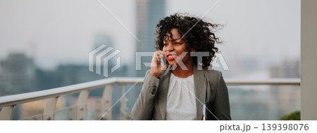 A businesswoman standing on terrace in modern office, making phone call. A businesswoman standing on terrace in modern office, making phone call. 139398076