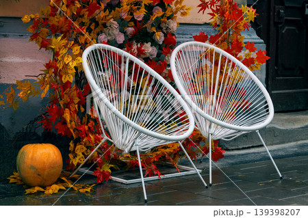 Two white chairs on a wet urban street decorated with autumn leaves and a pumpkin Two white chairs on a wet urban street decorated with autumn leaves and a pumpkin 139398207
