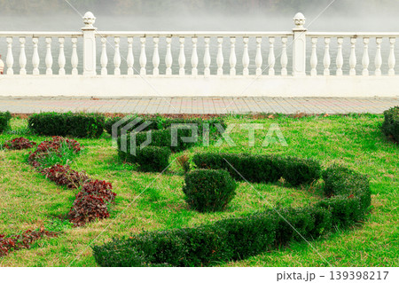 Manicured garden with ornate balustrade overlooking misty water Manicured garden with ornate balustrade overlooking misty water 139398217