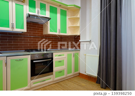Modern kitchen interior with green cabinets and brown brick backsplash 139398250