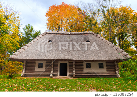 Traditional Ukrainian log house with thatched roof surrounded by autumn foliage 139398254