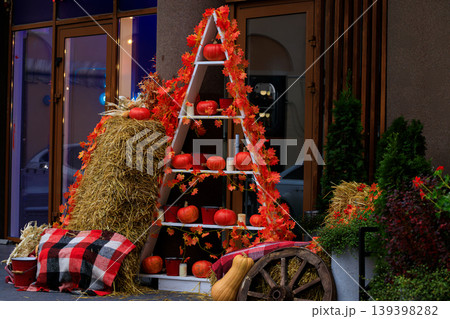 Charming Halloween cottage core street decor with pumpkins and hay bales 139398282