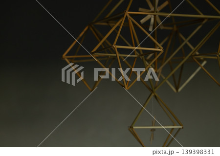 Geometric straw ornament hanging indoors with soft focus and warm lighting dusk interior abstraction 139398331