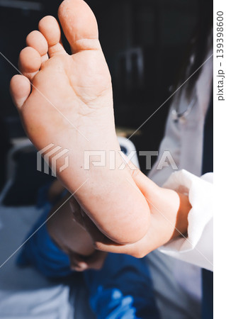 Doctor examining and supporting injured ankle of female patient in hospital room, providing medical assistance and treatment for sprain or fracture Doctor examining and supporting injured ankle of female patient in hospital room, providing medical assistance and treatment for sprain or fracture 139398600