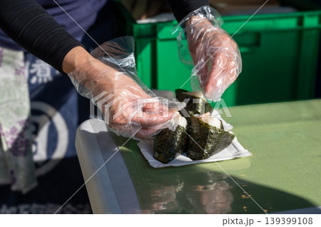 Vendor molds rice. Casual market scene where vendor expertly shapes onigiri for customers 139399108