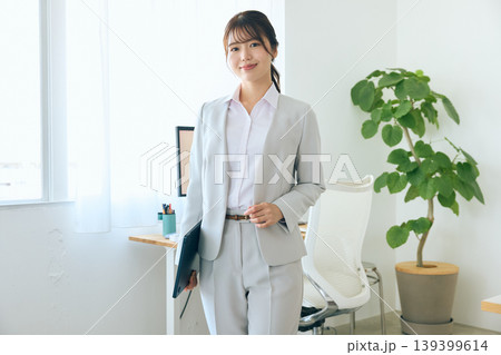 明るいオフィスでタブレットを持ち微笑むスーツ姿の若い女性ビジネスパーソン・新入社員のポートレート 明るいオフィスでタブレットを持ち微笑むスーツ姿の若い女性ビジネスパーソン・新入社員のポートレート 139399614