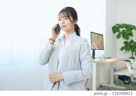 スマートフォンで通話する若い女性ビジネスパーソン・オフィスで電話対応する会社員 139399621