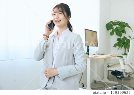 スマートフォンで通話する若い女性ビジネスパーソン・オフィスで電話対応する会社員 スマートフォンで通話する若い女性ビジネスパーソン・オフィスで電話対応する会社員 139399623