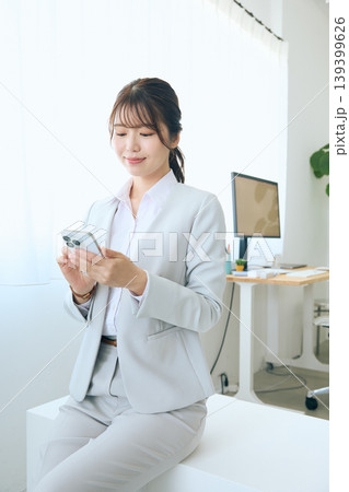 スマートフォンを操作する若い女性ビジネスパーソン・オフィスで連絡を確認する会社員 スマートフォンを操作する若い女性ビジネスパーソン・オフィスで連絡を確認する会社員 139399626