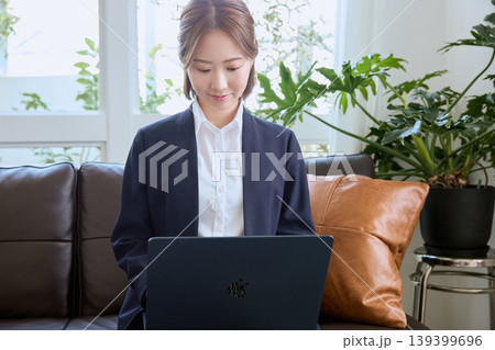 ソファに座りノートパソコンで仕事をするスーツ姿の若い日本人女性ビジネスパーソン・リモートワークのイメ 139399696