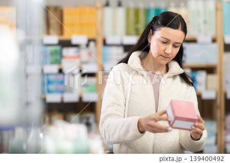 woman chooses a package of pills in a pharmacy 139400492