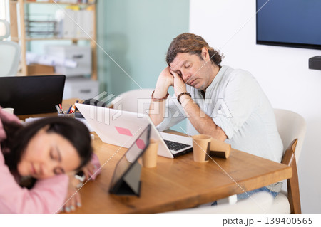 Tired female office worker having nap while sitting in workplace 139400565