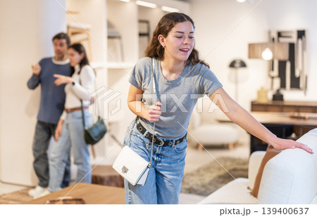 Happy girl choosing a new sofa in furniture store Happy girl choosing a new sofa in furniture store 139400637