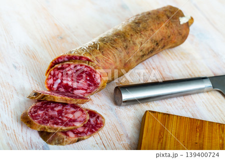 Thin salchichon sausage slices on wooden background, view from above Thin salchichon sausage slices on wooden background, view from above 139400724