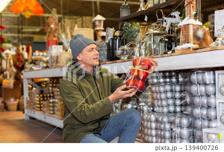 Man choosing christmas balls in decorative goods store Man choosing christmas balls in decorative goods store 139400726