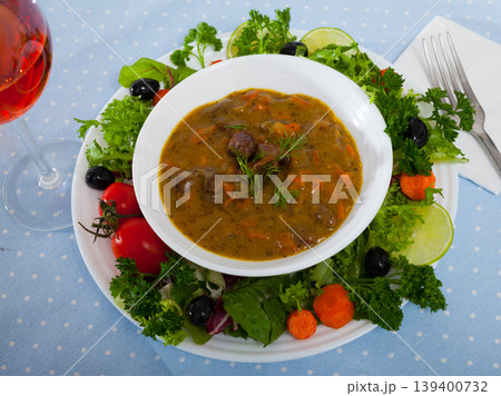 Tasty goulash from chicken hearts with lettuce at plate, fresh vegetables 139400732