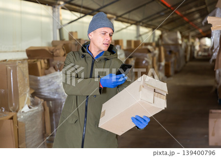 Warehouse worker photographing cardboard box with his phone 139400796