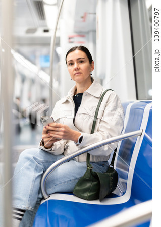 European woman sitting on seat in subway train and using smartphone European woman sitting on seat in subway train and using smartphone 139400797