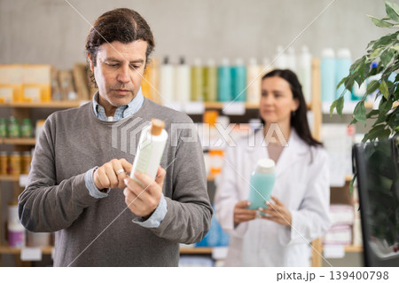 man chooses a cream in a pharmacy against the background of a consultant man chooses a cream in a pharmacy against the background of a consultant 139400798
