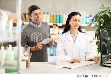 man with a medical prescription consults a pharmacist 139400802