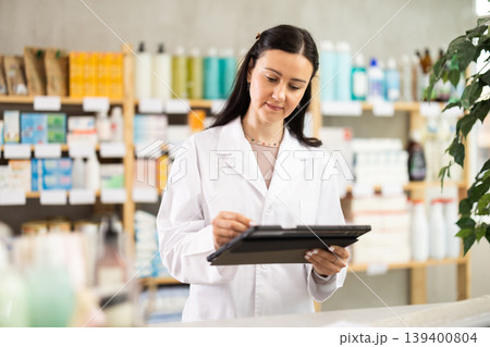 Woman pharmacist makes restock, uses electronic carrier tablet of information Woman pharmacist makes restock, uses electronic carrier tablet of information 139400804