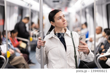 In the subway car, woman with mobile phone makes a selfie or scans QR code In the subway car, woman with mobile phone makes a selfie or scans QR code 139400821