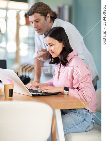 Man helping female colleague in work in coworking space 139400861