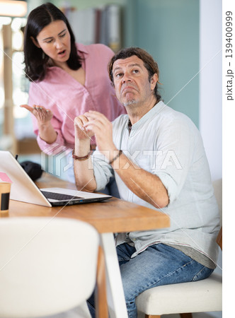 Adult woman scolding adult male colleague working on laptop Adult woman scolding adult male colleague working on laptop 139400999