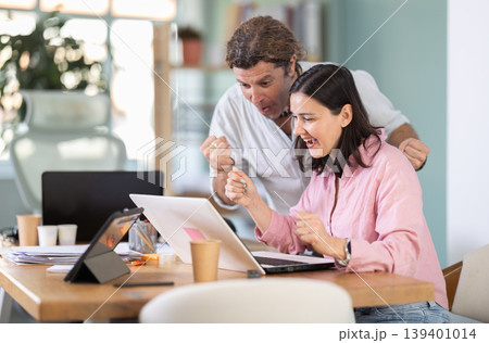 Happy colleagues sharing success while looking at laptop screen 139401014