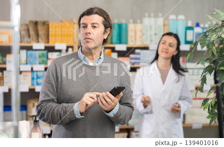 Adult man with phone choosing medicines and hygiene products 139401016