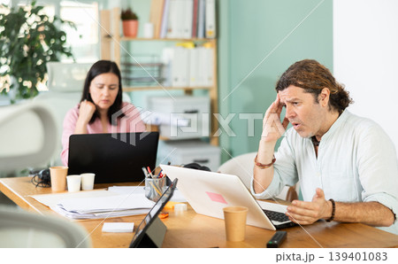 Sad and puzzled man working on laptop with problems in office 139401083