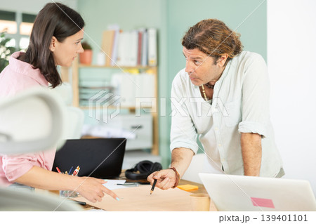 Two architects discuss a building plan in company office Two architects discuss a building plan in company office 139401101